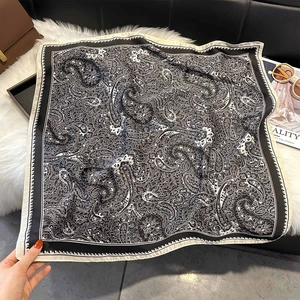 Détail d'un carré de soie à motif paisley avec bordures contrastées et texture légère