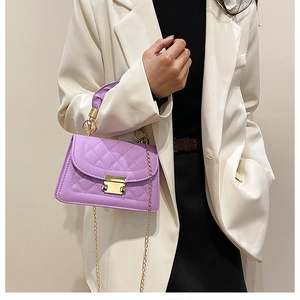 Detalle de bolso acolchado lavanda con cadena dorada sobre una chaqueta blazer blanca