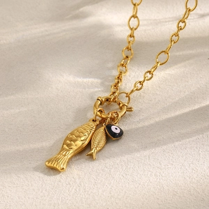 Detail of 18K gold-plated chunky chain necklace with fish pendants and evil eye charm