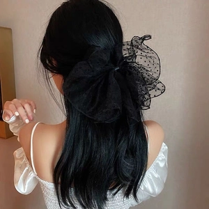 Detailed back view of a large black polka dot mesh bow hair clip on model hair