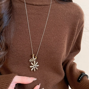 Detailed macro view of golden daisy pendants with tiger eye beads on a winter sweater