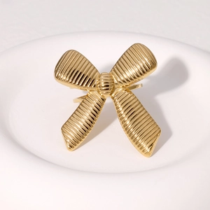 Minimalist 18k gold butterfly ring with striped texture on a white decorative dish