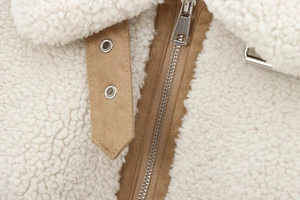 Détail macro d'une veste en polaire avec garniture en cuir brun et fermeture éclair métal