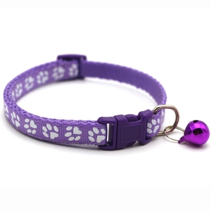 Detail of purple nylon pet collar with white paw prints, buckle, and purple bell
