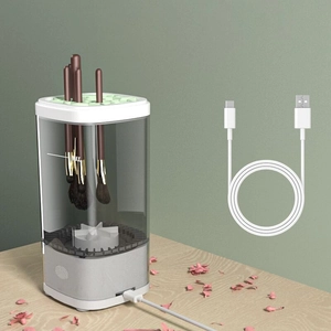 Detail view of a white automatic makeup brush cleaner on wood with a USB charging cable