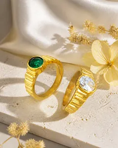 Detail von goldfarbenen Ringen mit grünem und weißem Edelstein und Wellenstruktur