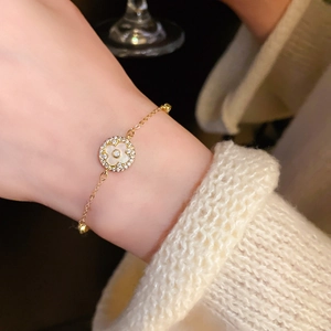 Detailed view of a gold clover bracelet with white mother-of-pearl and crystal pavé