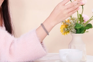 Detailed view of triple-layer stainless steel pearl chain bracelet on a female wrist