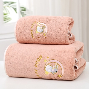 Pink coral fleece bath towels featuring moon rabbit embroidery in a stack
