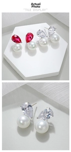 Macro detail of luxury teardrop zircon and round pearl earrings on white fabric
