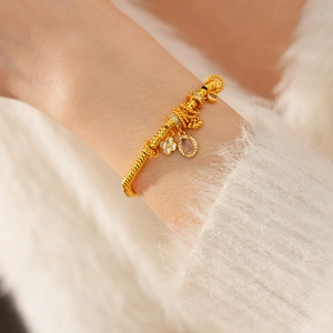 Macro detail of a 24k gold plated flower bracelet with oval zircon charms on female wrist