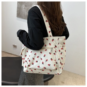 Detail of white corduroy tote bag with red strawberry pattern and exterior zip pocket