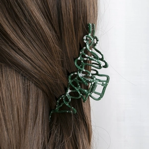 Irregular liquid metal hair claw in dark green with white splatter on brown hair