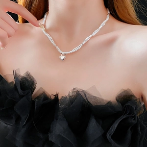 Gros plan d'un collier de perles double couche avec pendentif cœur argenté sur le cou