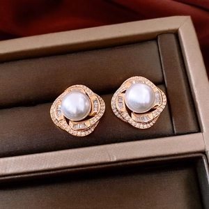 Macro shot of French luxury pearl earrings with rose gold swirls and zircons in a box