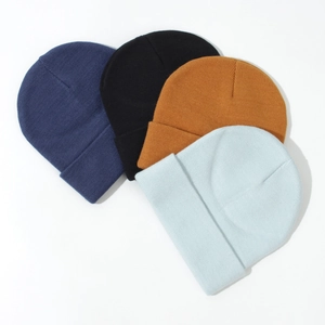 Flat lay of knit beanies in navy, black, yellow, and light blue on white background