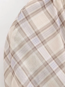Close-up of beige plaid fabric with brown and purple lines showing woven texture