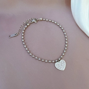Macro shot of silver beaded chain bracelet with a heart charm in stainless steel
