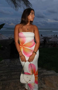 Close-up of strapless maxi dress featuring tropical pink plumeria floral print on beach
