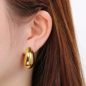 Macro shot of polished gold water drop earrings showing high glossy metal finish