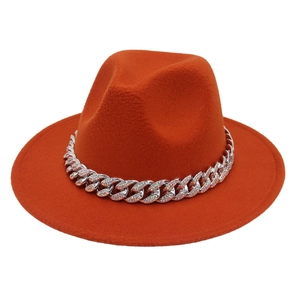Detail of orange fedora hat featuring a silver Cuban chain with colorful rhinestones