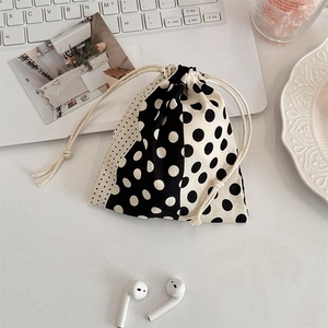 Polka dot drawstring storage bag on desk with laptop and wireless earphones