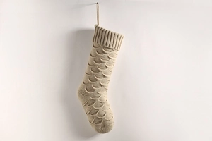 Detail of beige knitted Christmas stocking with wave scale pattern and hanging loop