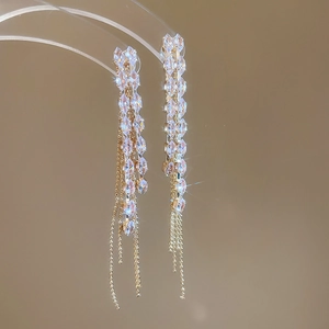 Macro shot of sparkling long tassel earrings with shimmering crystals and gold-tone finish