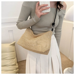 Detailed view of woven straw shoulder bag with elegant black strap and knotted texture