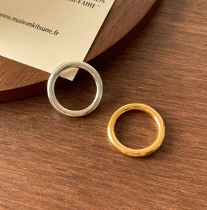 Close-up of minimalist gold and silver polished rings on a natural wood surface