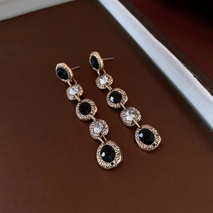 Close-up of vintage long gold tassel earrings with black and clear zircon stones