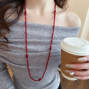 Close-up of elegant red crystal beaded necklace with gold spacers on a grey sweater