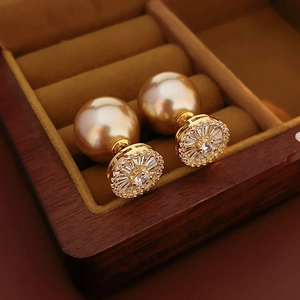 Détail de boucles d'oreilles dorées avec zircon et perles dans un écrin en bois élégant