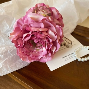 Detail of pink gradient rose claw clip on a wooden tray with elegant pearl accents
