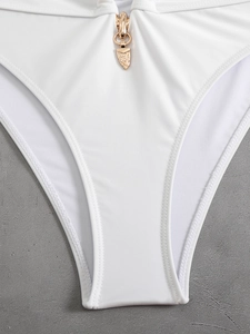 Detail of white bikini bottoms with a textured gold metal buckle on high-stretch fabric