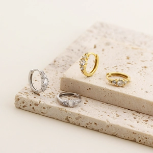 Detail of silver and gold huggie earrings with sparkling cubic zirconia on stone base