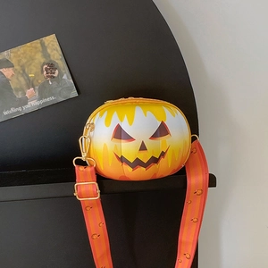 Detail of pumpkin-shaped crossbody bag with festive smiling face and striped strap
