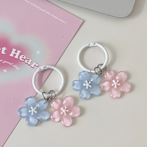 Close-up of pink and blue cherry blossom pendants with white circular clasp on a table