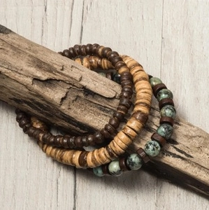 Close-up of three-piece ethnic beaded bracelets with wood and stone beads on driftwood