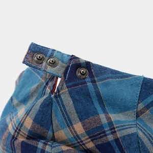 Detailed close-up of vintage metal snap buttons on a blue and brown checkered fabric cap