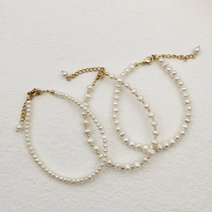 Close-up of three handmade freshwater pearl bracelets with gold beads and lobster clasp