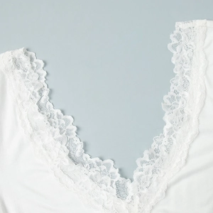 Détail de la bordure en dentelle florale blanche sur un décolleté en V plongeant