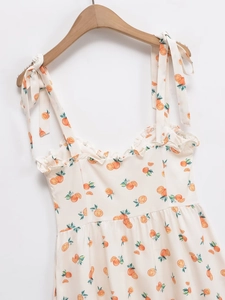 Détail de robe d'été courte imprimé orange avec bretelles à nœuds et col à volants