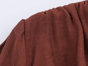 Macro detail of reddish-brown dress showing high-quality textured fabric and shoulder seam