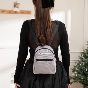 Mini seersucker striped backpack for women with black nylon straps in a cozy setting