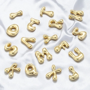 Macro shot of polished gold bubble alphabet beads for DIY jewelry on white silk