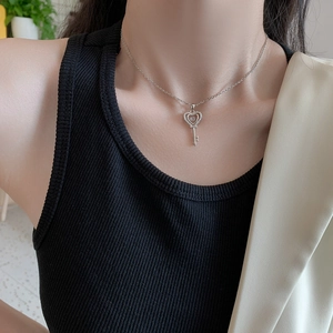 Collier clé en forme de cœur argenté avec pierres brillantes sur le cou du mannequin