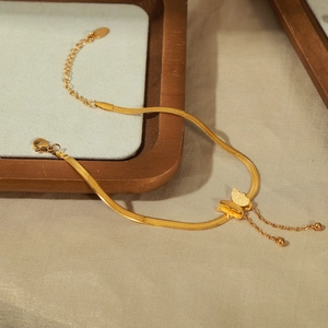 Elegant gold titanium steel double-layered butterfly tassel anklet on a wooden display tray