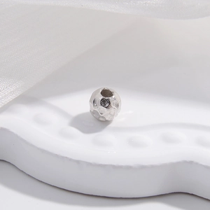 Macro detail of silver S925 beaded charm with irregular faceted hammer texture finish