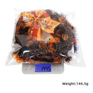 Detail showing Halloween wreath weight of 144.5g with orange pumpkin bow and black tinsel